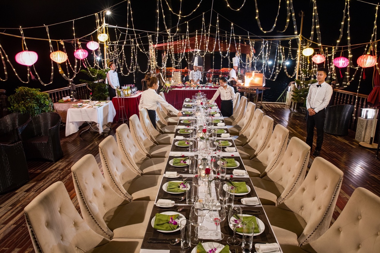Dinner table on Halong Bay cruise with elegant settings and string lights, perfect for a luxurious t.