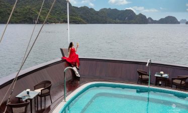 Stunning view of Halong Bay from a cruise balcony with a woman enjoying the scenery and relaxing atm.