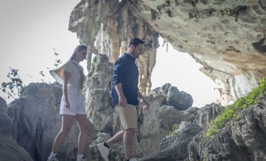 Exploring Halong Bay caves with travelers on a scenic cruise balcony.