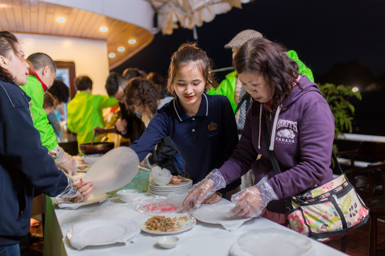 People serving and enjoying traditional food at a cultural dinner in Vietnam.
