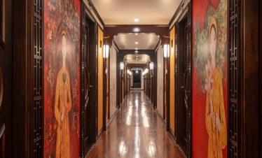 Hallway corridor with traditional Asian artwork on cruise ship, elegant wooden floors, warm lighting.