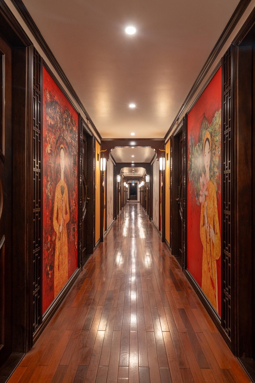 Hallway corridor with traditional Asian artwork on cruise ship, elegant wooden floors, warm lighting.