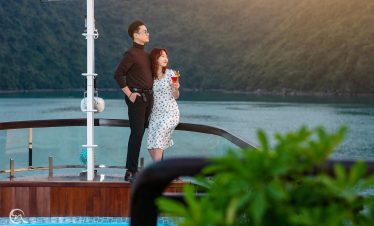 Romantic couple enjoying scenic view from cruise balcony in Halong Bay, Vietnam.