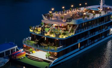 Luxurious dinner cruise boat on the river at night with scenic lighting and outdoor deck, Vietnam travel experience.