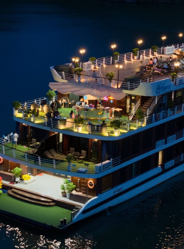 Luxurious dinner cruise boat on the river at night with scenic lighting and outdoor deck, Vietnam travel experience.