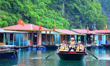 Colorful floating houses in Halong Bay, Vietnam, with tourists enjoying boat tours and scenic views.