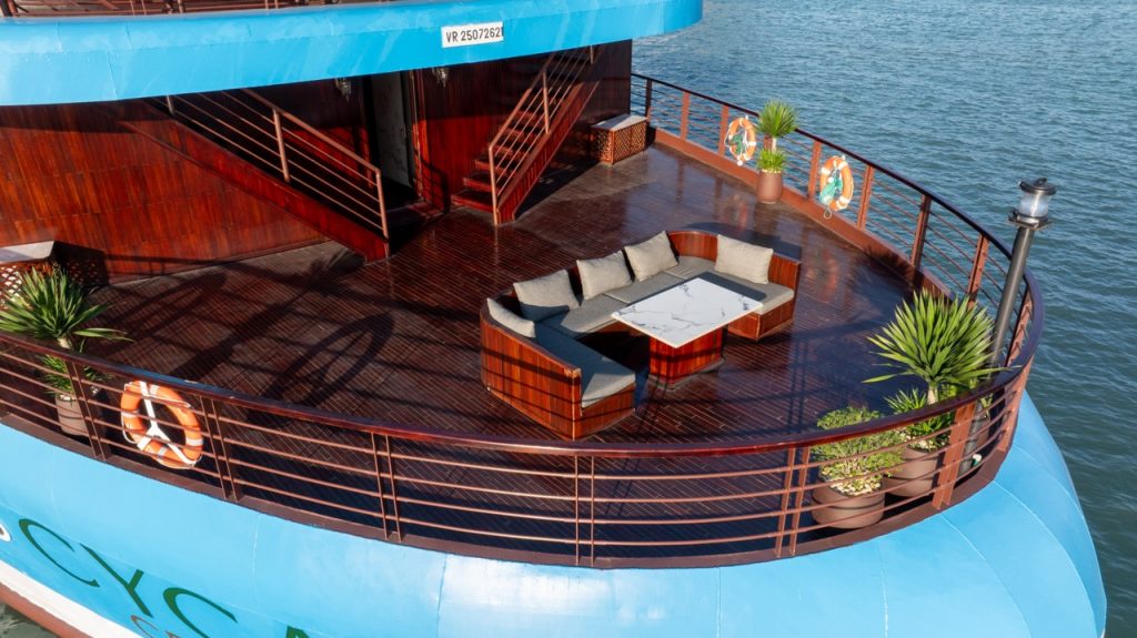Luxury cruise balcony with seating area overlooking Halong Bay waters.