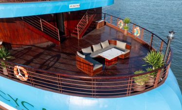 Luxury cruise balcony with seating area overlooking Halong Bay waters.