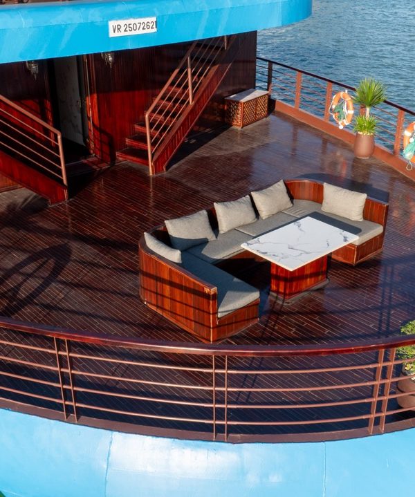 Luxury cruise balcony with seating area overlooking Halong Bay waters.