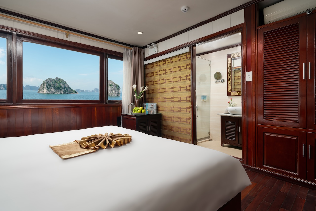 Stunning view from a luxury cruise cabin overlooking Halong Bay's emerald waters and limestone islan.