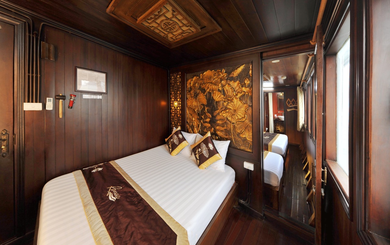 Cozy cruise cabin with elegant wooden decor and scenic window views in Bai Tu Long Bay.