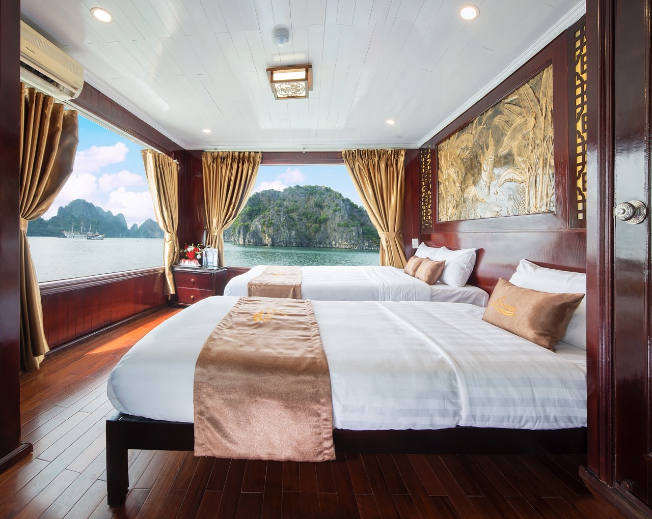 Elegant cruise cabin with panoramic bay views and plush bedding in Bai Tu Long Bay.
