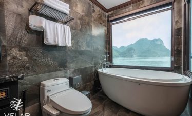Stunning Halong Bay cruise balcony with mountain views and luxurious bathroom.