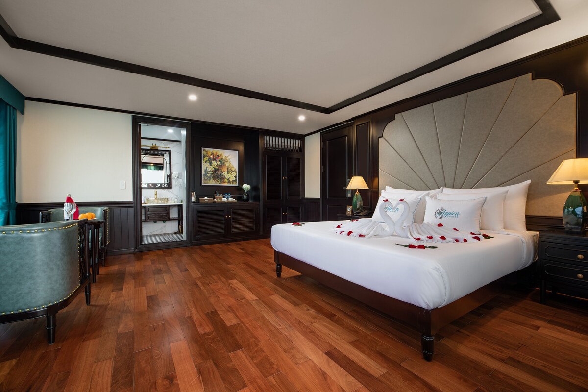 Elegant hotel room with king-sized bed, romantic towel art, and luxurious decor for a memorable stay.