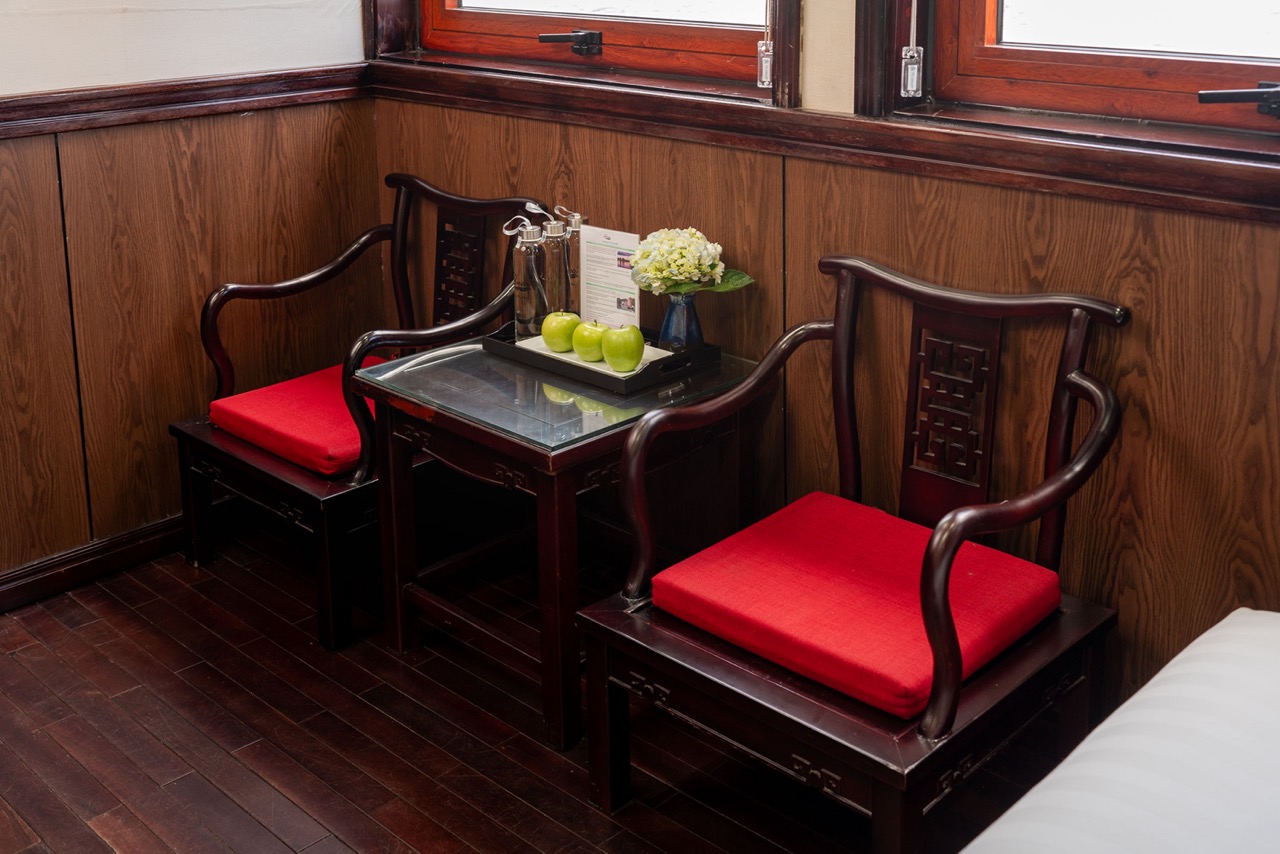 Beautiful cruise balcony with wooden furniture and scenic views of Halong Bay, perfect for relaxing.