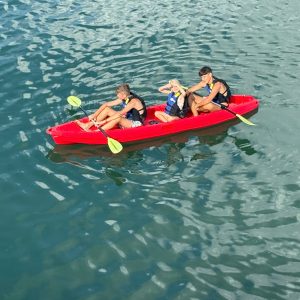 Kids kayaking adventure in clear water with safety vests and paddles for fun outdoor activity.