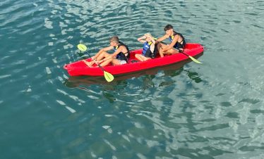 Kids kayaking adventure in clear water with safety vests and paddles for fun outdoor activity.