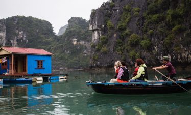 Enjoy a peaceful boat ride in Bai Tu Long Bay surrounded by lush green cliffs and calm waters.