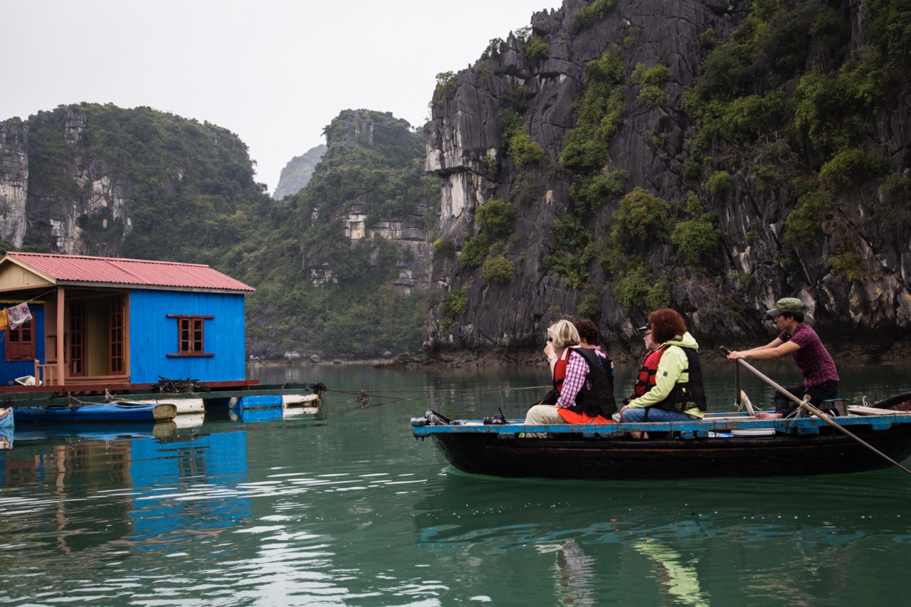 Enjoy a peaceful boat ride in Bai Tu Long Bay surrounded by lush green cliffs and calm waters.