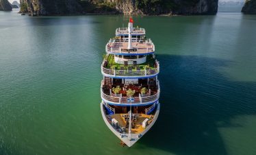 Elegant cruise ship floating on Halong Bay with lush limestone karsts in the background.