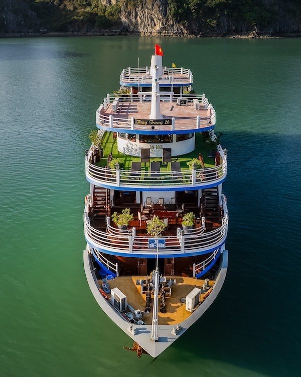 Elegant cruise ship floating on Halong Bay with lush limestone karsts in the background.