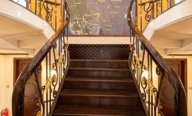 Elegant staircase inside Bai Tu Long cruise ship with classic design and warm lighting.