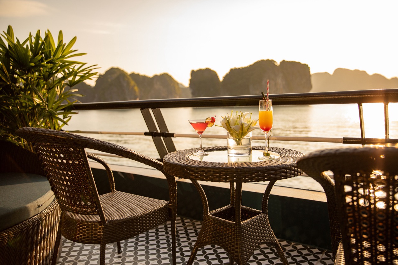 Relaxing Halong Bay cruise balcony with stunning sunset views and luxurious ambiance.