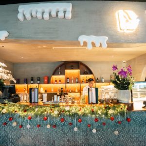 Cozy hotel bar decorated with festive garlands, flowers, and holiday ornaments for Christmas.