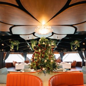 Cozy boat interior with Christmas decorations, plush seating, and scenic water views.
