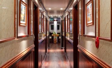 Elegant cruise corridor with wooden accents and framed artwork, perfect for exploring Halong Bay.
