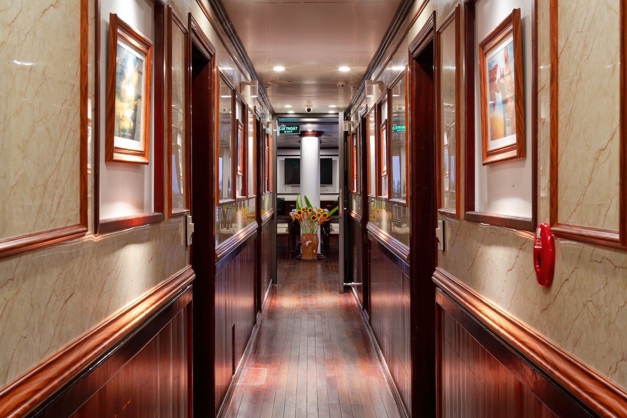 Elegant cruise corridor with wooden accents and framed artwork, perfect for exploring Halong Bay.