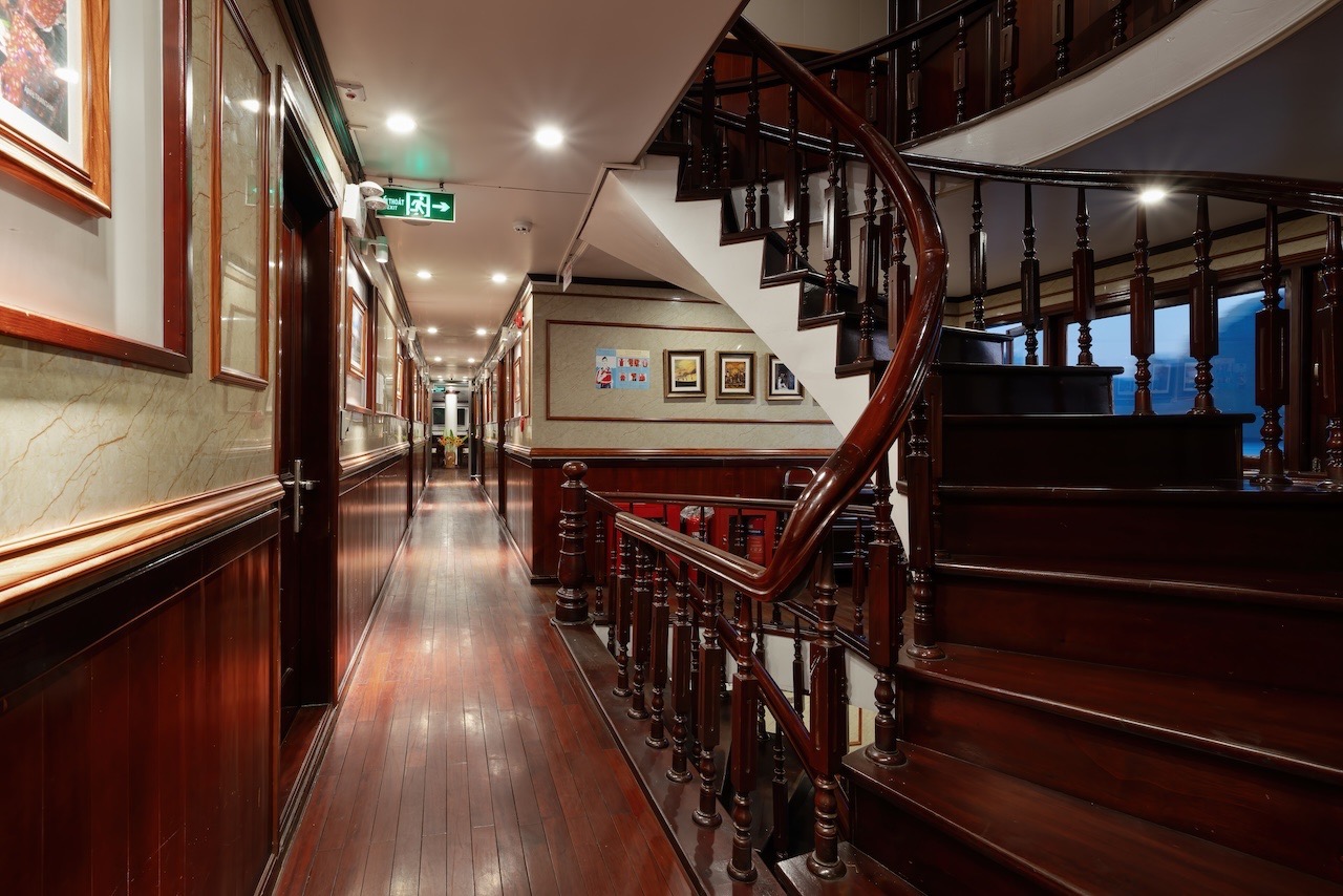 Elegant cruise interior with wooden staircase and classic decor in Halong Bay.