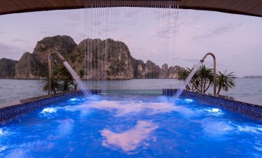 Relaxing cruise balcony view of Halong Bay with scenic limestone karsts and calm waters.