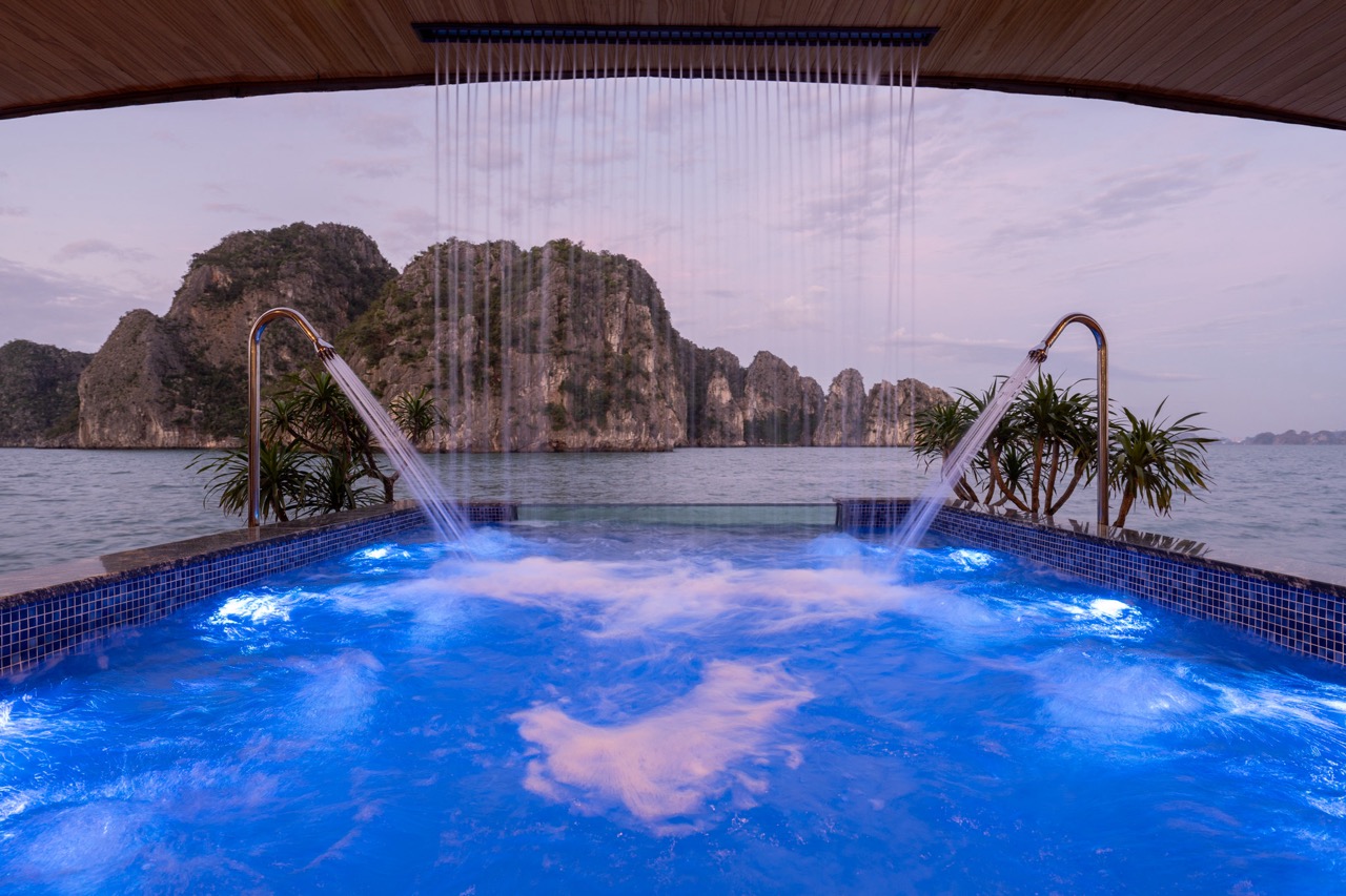 Relaxing cruise balcony view of Halong Bay with scenic limestone karsts and calm waters.