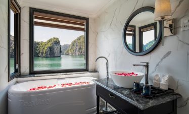 Stunning view of Halong Bay from a luxurious cruise balcony with relaxing bath and scenic limestone.