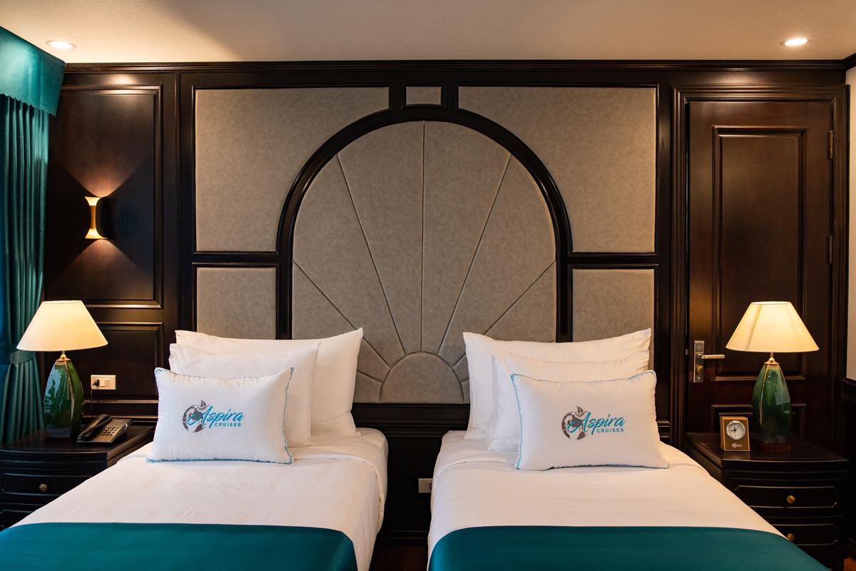 Luxury hotel bedroom with twin beds and elegant dark wood decor in Vietnam.