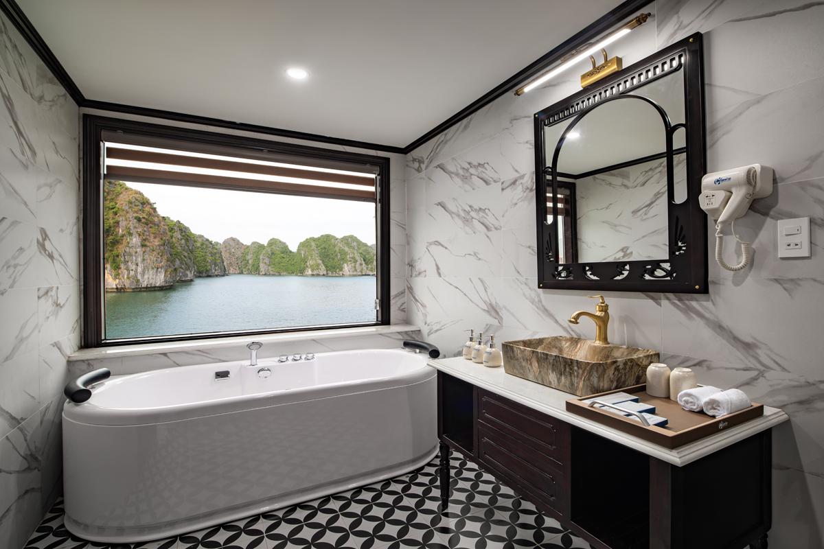 Luxury bathroom with bathtub and scenic ocean view through large window.