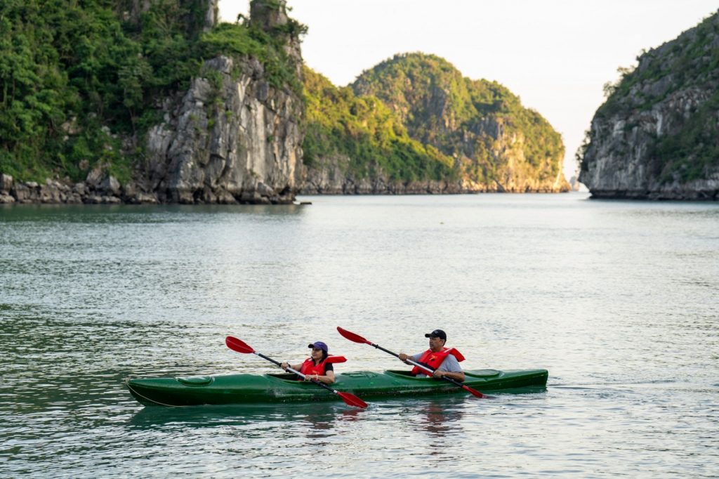 Kayaking in Halong Bay with scenic limestone islands and tranquil waters, perfect for adventure trav.