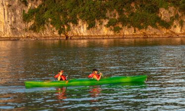 Kayaking adventure on Halong Bay cruise balcony with scenic limestone cliffs.