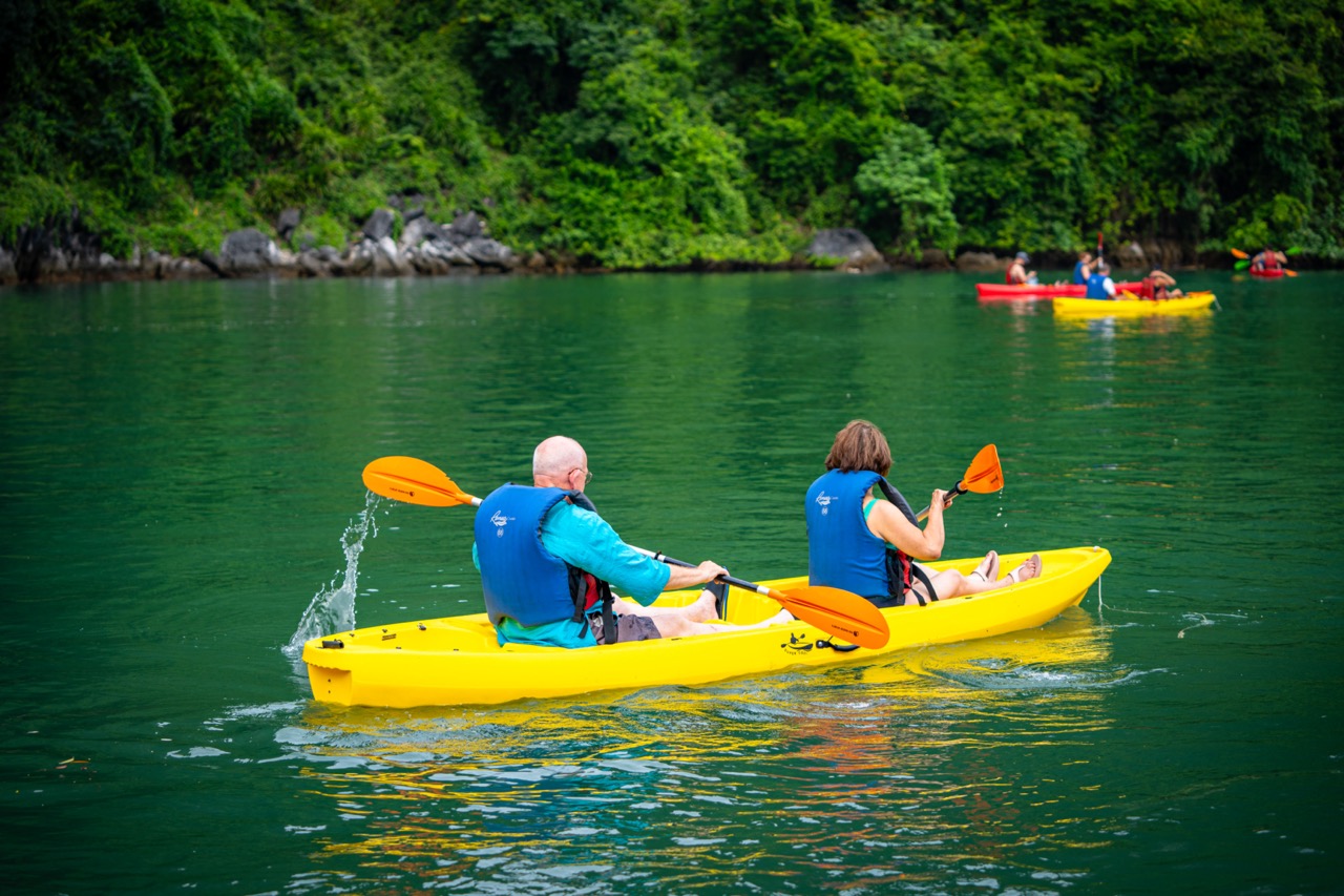 Kayaking in Halong Bay with lush green scenery and tranquil waters, perfect for an adventurous day o.