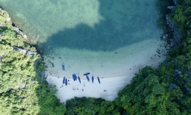 Aerial view of Halong Bay with cruise boats and turquoise waters, showcasing scenic limestone karsts.