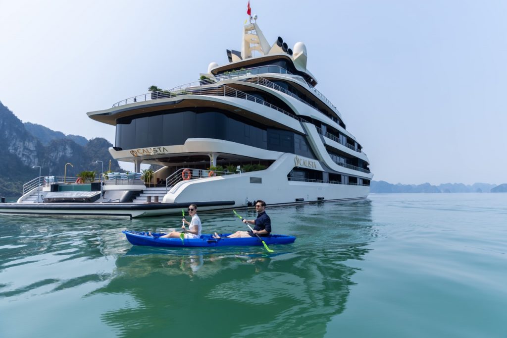 Elegant cruise balcony view in Halong Bay with people kayaking and enjoying the scenery.