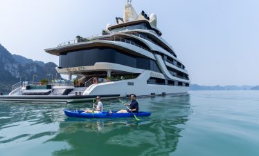 Elegant cruise balcony view in Halong Bay with people kayaking and enjoying the scenery.
