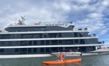 Halong Bay cruise balcony with kayaker enjoying scenic views and tranquil waters.