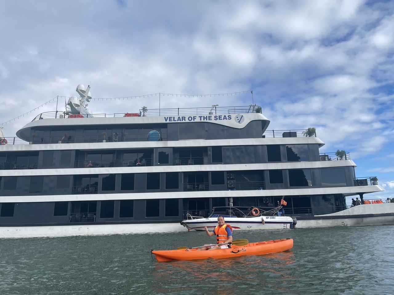 Halong Bay cruise balcony with kayaker enjoying scenic views and tranquil waters.