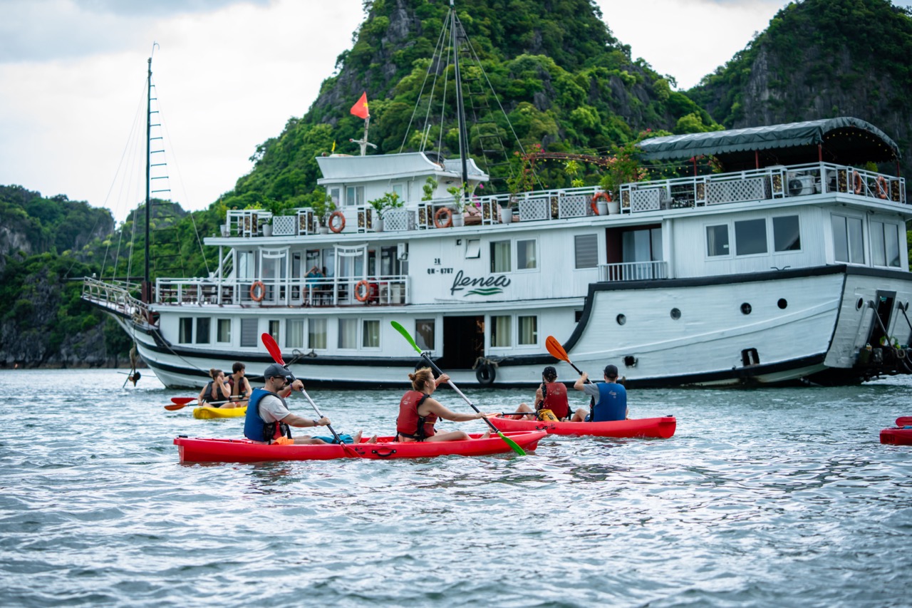 Kayaking adventure on Bai Tu Long Bay cruise balcony with scenic limestone islands.