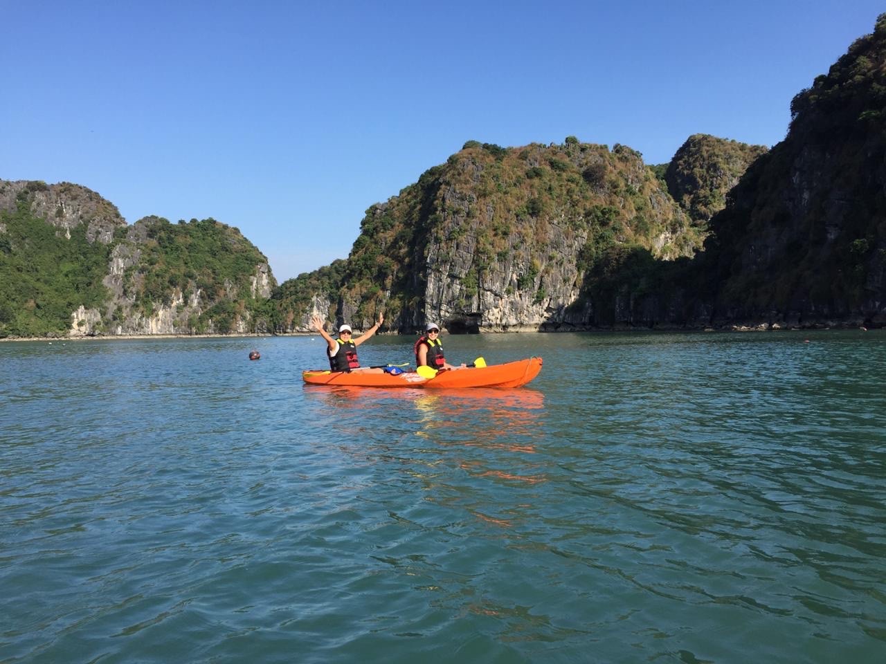 Kayaking in Halong Bay with scenic limestone karsts and tranquil waters, perfect for adventure and r.