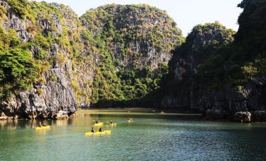 Stunning view of Halong Bay with kayakers exploring emerald waters and towering limestone karsts.