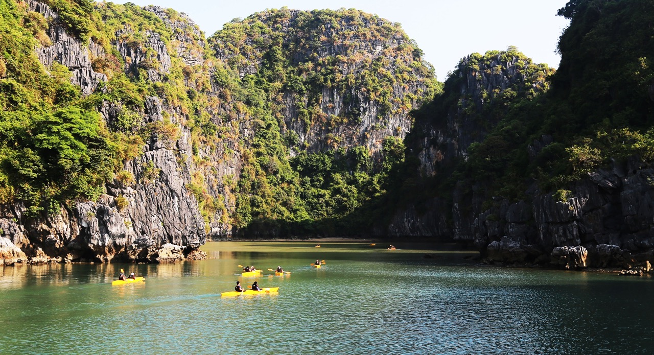 Stunning view of Halong Bay with kayakers exploring emerald waters and towering limestone karsts.
