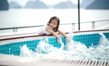 Child playing in hot spring pool with scenic mountain and lake view in Vietnam.